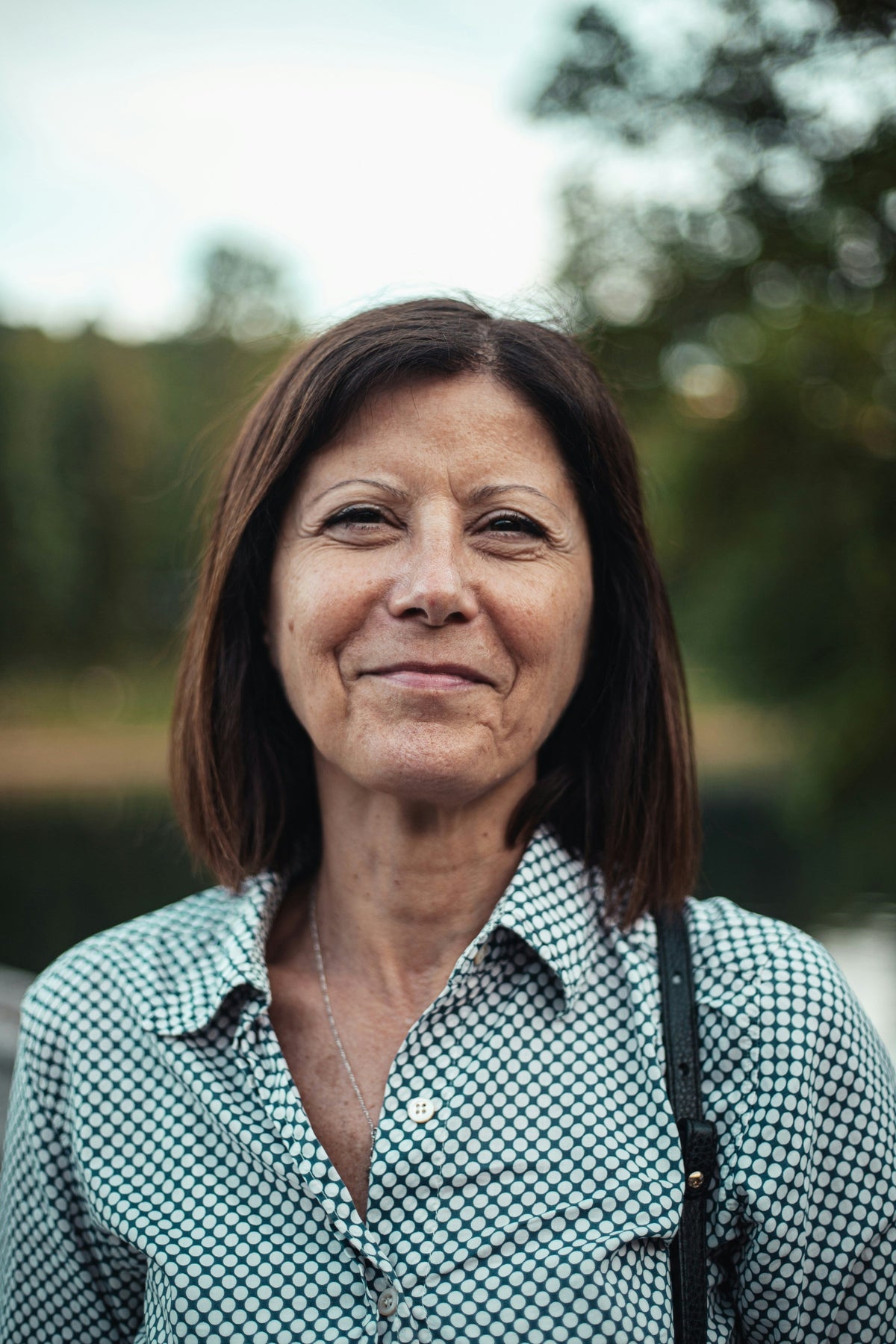 Woman in her fifties with dark hair smiling outdoors