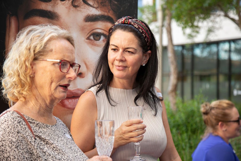 Two guests laughing together, one holding a glass of sparkling wine, at a previous SWA event