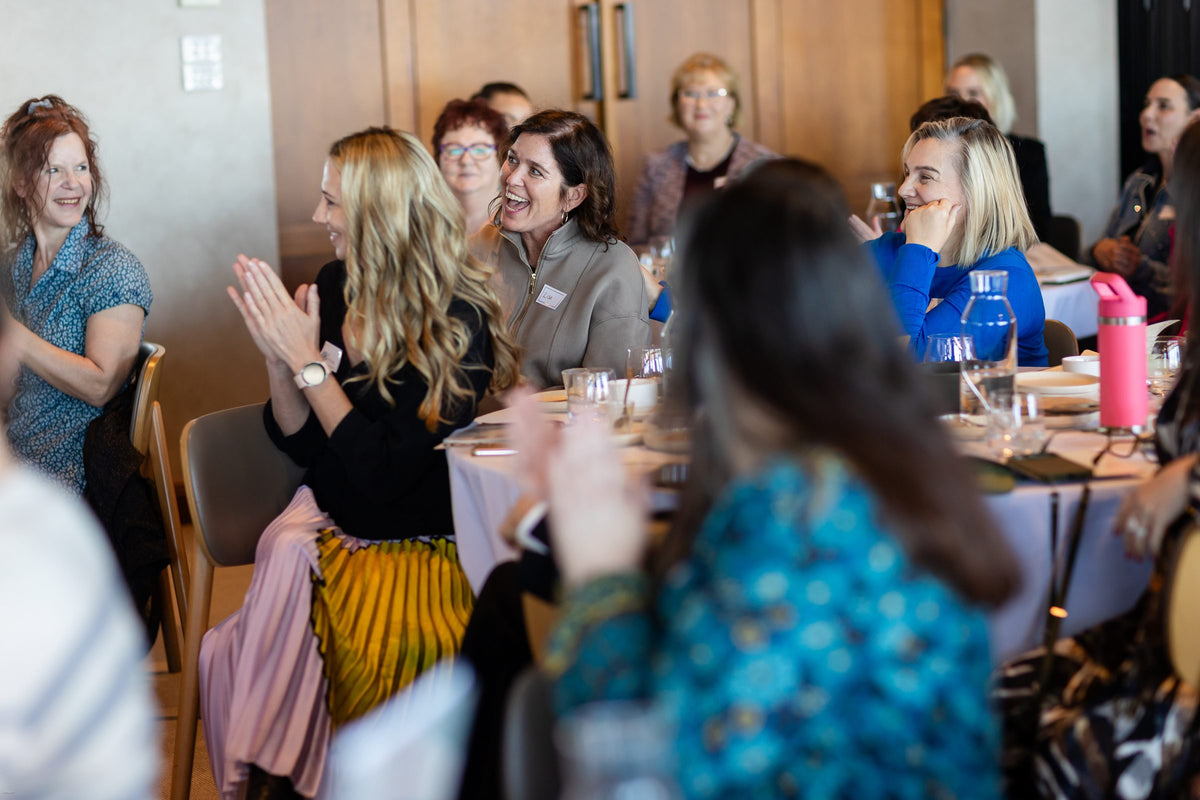 Guests clapping and smiling at their tables during Thrive Through Change 2026