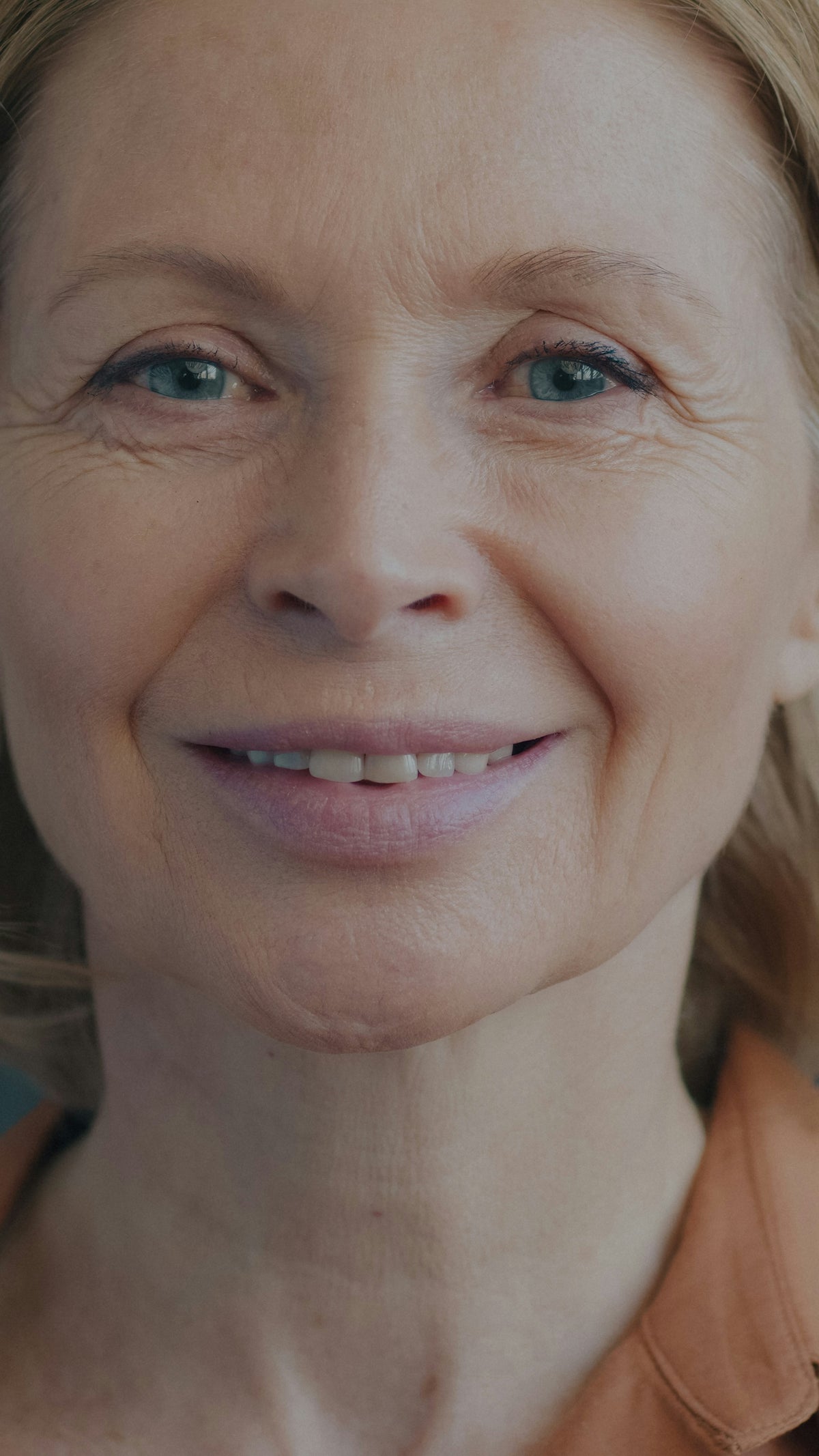 Close portrait of a smiling woman in her fifties with smile lines and a softening jawline