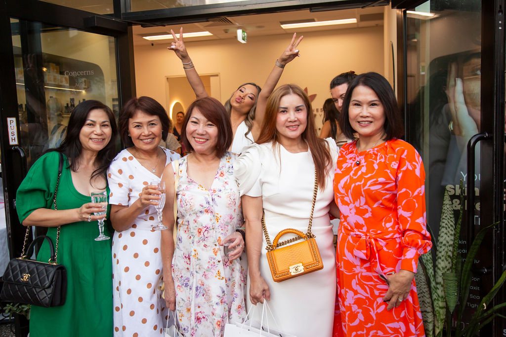 Smiling guests celebrating with drinks at the Skin Wellness Academy entrance