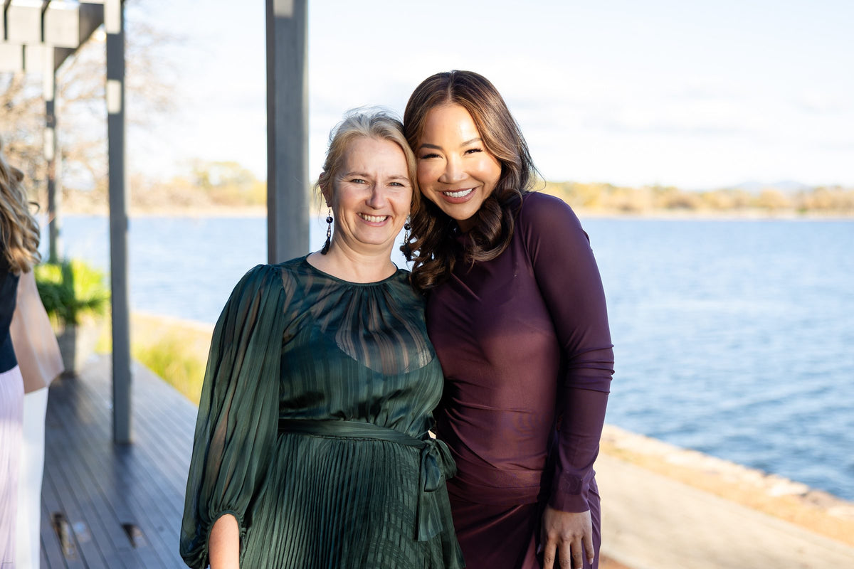 Two women embracing beside the lake at golden hour at Thrive Through Change 2026
